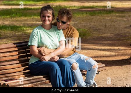 A couple sits on a park bench and enjoys the warmth of an fall day The man, who has a visual-spatial disorder, and the woman, who has an intellectual Stock Photo