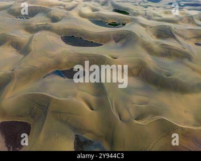 A drone captures the vast and sculpted Maspalomas Dunes at sunset, showcasing the textures and patterns created by natural forces, In Gran Canary Isla Stock Photo