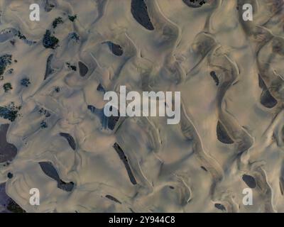 Drone capture of the sprawling, textured landscape of Maspalomas Dunes, highlighting the shifting sands and isolated vegetation patches Stock Photo