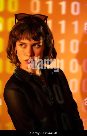 A young woman with brown hair and a sparkly gold top. The background features soft, dreamy pastel colors that create a vivid yet gentle ambiance aroun Stock Photo