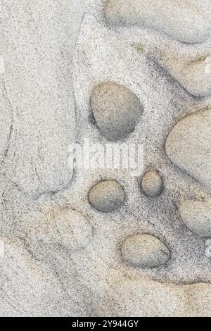This image captures the intricate patterns and subtle colors of a natural sandstone surface, highlighting its smooth textures and circular indentation Stock Photo