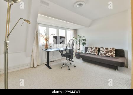 A contemporary home office featuring a desk with computer and chair, floor lamp, and a cozy sofa with decorative pillows. Stock Photo