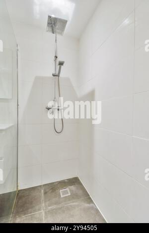 Modern shower corner with a large overhead and handheld showerhead in a white tiled bathroom. Stock Photo