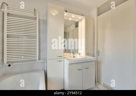 A sleek and modern bathroom design featuring a white vanity, bathtub, and tiled walls bathed in natural sunlight. Stock Photo