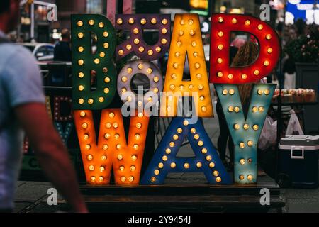 A vibrant, illuminated Broadway sign in Times Square, New York City. The colorful letters with light bulbs capture the iconic and bustling atmosphere Stock Photo