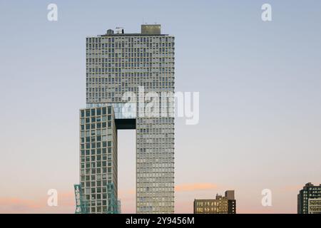 A striking modern skyscraper in New York, featuring a unique geometric design with an elevated section connecting two sections of the building. The cl Stock Photo