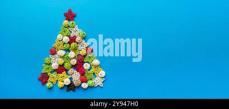 Christmas tree made from colored handmade ball decoration on colored background, view from above. New Year minimal concept with copy space. Stock Photo