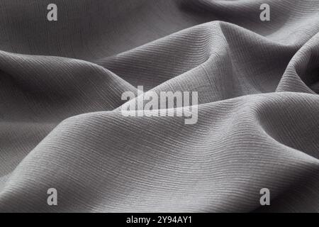 Close-up of textured gray fabric with gentle folds and natural light highlights Stock Photo