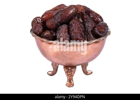 A close-up of dried dates in an ornate copper bowl, isolated on a white background Stock Photo