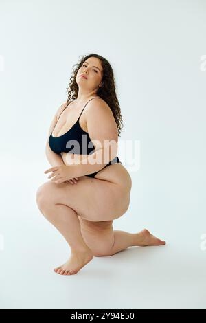 A beautiful plus size woman poses gracefully, showcasing confidence and self love in a studio. Stock Photo