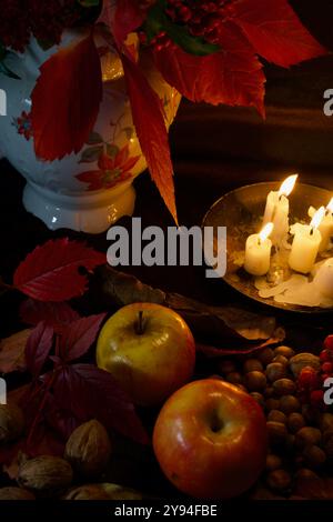 Still life of a vase with flowers, fruits and candles. Stock Photo