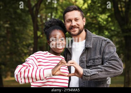 International relationships. Lovely couple making heart with hands outdoors Stock Photo