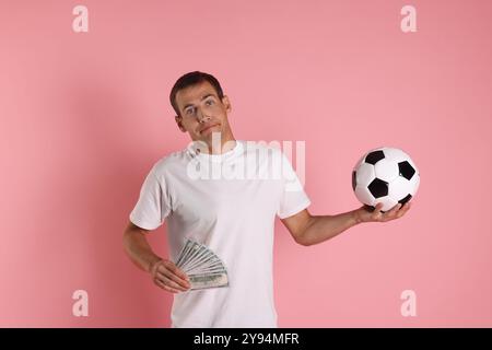 Man with money and soccer ball on pink background Stock Photo