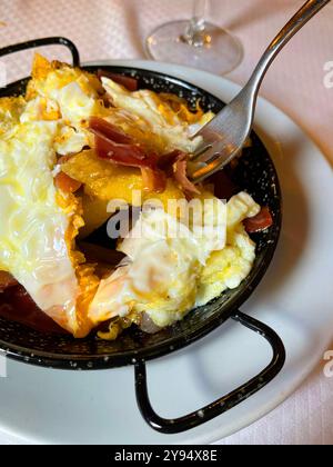 Eating scrambled eggs with ham and potatoes. Spain. Stock Photo