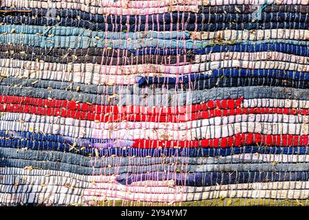 Old homespun doormat made from strips of cloth as background. Handmade texture of a rug from different fabrics Stock Photo