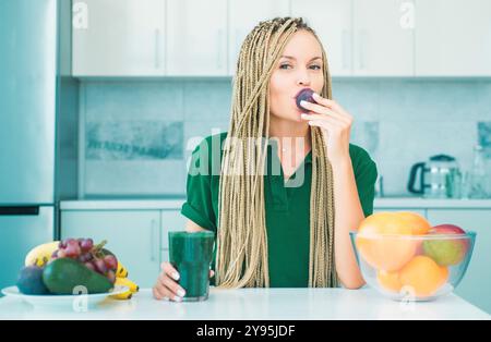 Organic natural cocktail with blackberry. Vegan meal and detox menu. Smiling young woman drinking green smoothie in kitchen. Superfood. Diet and Stock Photo