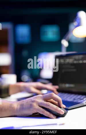 Closeup of person coding at his desk, typing on digital laptop and using a mouse, managing database systems. Working independently, an individual excels in cyber security and machine learning. Stock Photo