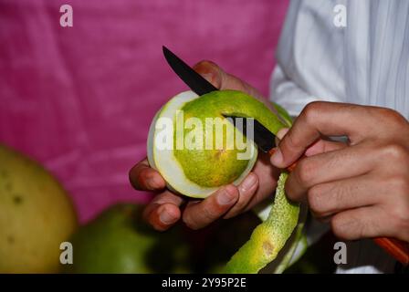 Man peeling orange skin using a knife, preparing slicing fruits for eaten. concept of preparing fruits Stock Photo