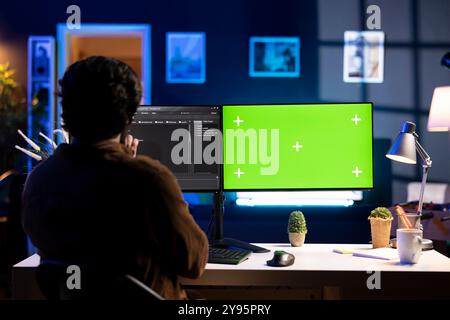 Cybersecurity expert using green screen computer to look for security vulnerabilities and injected malware. Programmer installing fortified code on chroma key PC to prevent cyber attacks Stock Photo