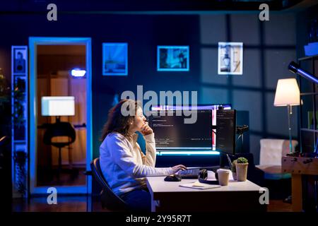 System administrator doing software debugging on PC at home, checking broken lines of code displayed on AR hologram. IT professional in living room fixing coding problems using augmented reality Stock Photo