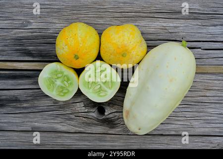Lemon cucumber (one cut in half) and White Parisian cucumber on a wooden board - Cucumis sativa 'Lemon' and Cucumis sativus L, Herault, France Stock Photo