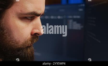 Software engineer concerned, concentrating on finding bugs while coding on computer, extreme close up. Troubled IT professional frowning while looking at screen, confused by script errors, camera B Stock Photo