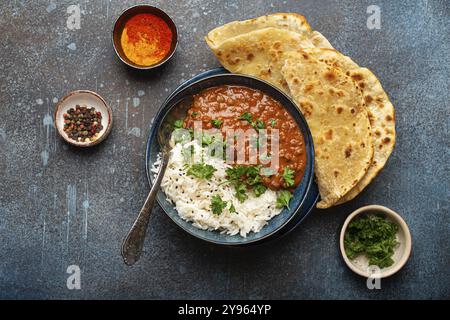 Traditional Indian Punjabi dish Dal makhani with lentils and beans in black bowl served with basmati rice, naan flat bread, fresh cilantro and spoon o Stock Photo