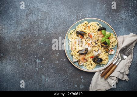 Italian seafood pasta spaghetti with mussels, shrimps, clams in tomato sauce with green basil on plate on rustic blue concrete background overhead. Me Stock Photo