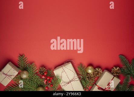 Christmas or New Year celebration red paper festive background with decoration fir tree, wrapped present boxes, cones, berries, sparkly red balls. Spa Stock Photo