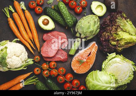 Assorted food raw products: vegetables, beef meat steak, fish salmon fillet on dark rustic brown stone table top view. Healthy food background, ingred Stock Photo