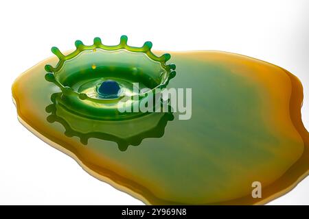 Water drop impact. High-speed photograph of secondary drop formation following the impact of a water droplet on water. The impact causes the surface of the pool to collapse, creating a rush of water inwards and upwards to form a column. Surface tension effects along the column cause a secondary drop to form. Shock waves radiate outwards as concentric circular ripples. Stock Photo
