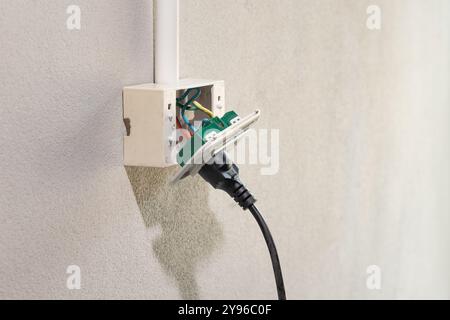 Dangerous broken electrical socket falling out of wall. Stock Photo