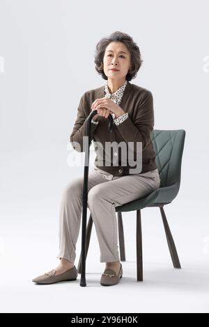 Senior woman sitting on a chair Stock Photo
