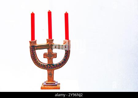 stylish handmade lamp in the form of a trident with three red candles on a light background Stock Photo