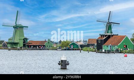 Windmills and tourists along the water at the Zaanse Schans in Zaandam Stock Photo