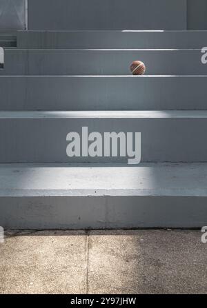 Old basketball ball on cement floor with Stairs leading and Natural light. use it as your Wallpaper, Poster and Copy space, Selective focus. Stock Photo
