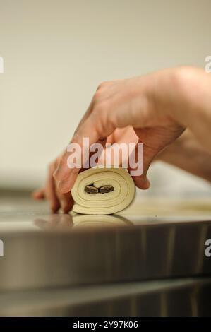 Close-up of baker's hands, bakery and pastry concept. Professional pastry chef making chocolate rolls. Stock Photo