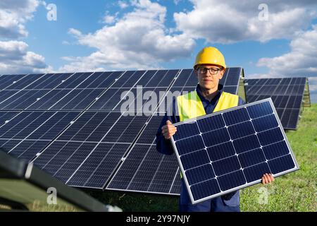 Worker with solar panel on a background of solar power station. Stock Photo