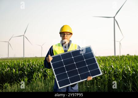 Worker with solar panel on a background of wind turbines. Stock Photo