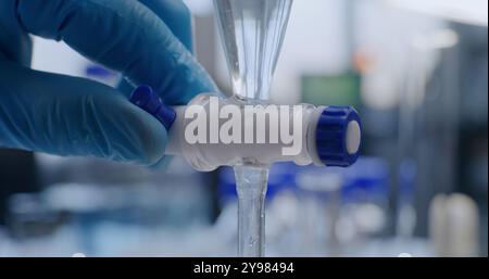 Advanced medical science lab: Close up of chemist pouring liquid from pipette into glass bottle. Professional scientist conducts chemical research, develops drugs using laboratory equipment. Chemistry Stock Photo