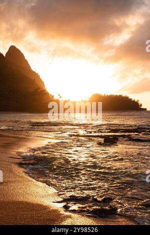 Picturesque sunset at Haena Beach and Tunnels Beach on Kauai with the sun setting behind the hills of Heana State Park (Hawaii, USA) Stock Photo