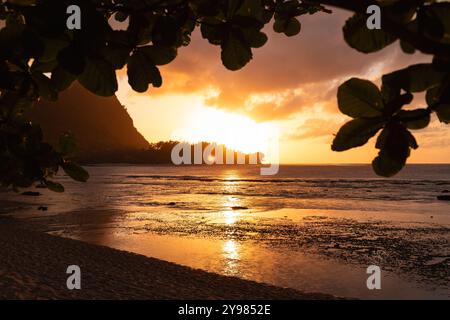 Picturesque sunset at Haena Beach and Tunnels Beach on Kauai with the sun setting behind the hills of Heana State Park (Hawaii, USA) Stock Photo