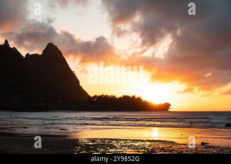 Picturesque sunset at Haena Beach and Tunnels Beach on Kauai with the sun setting behind the hills of Heana State Park (Hawaii, USA) Stock Photo