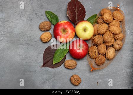Autumn composition with apples, walnuts and leaves on grey background Stock Photo
