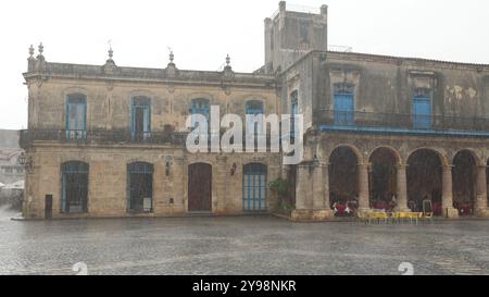 786 Hard rain almost hides the Casa Condes de Penalver House and the Palacio Marqueses Aguas Claras Palace on the Plaza Catedral Square. Havana-Cuba. Stock Photo