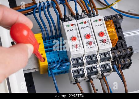 Technician Connecting Wires in Electrical Control Panel Stock Photo