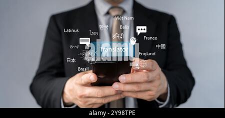 AI-Powered Language Translate App Concept. A person holds smartphone displaying an AI powered language translation app. Screen features robot and mult Stock Photo