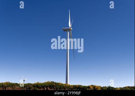 Wind turbine towering over Madeira’s lush hills under a bright blue sky, harnessing clean energy Stock Photo