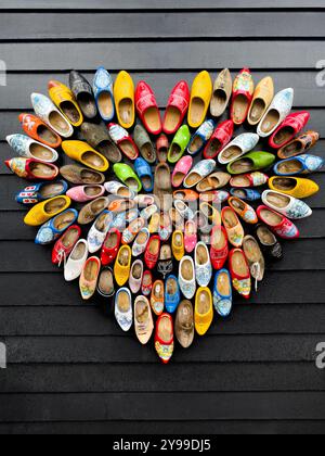 Multicolored traditional Dutch wooden Clogs on wooden wall. Stock Photo