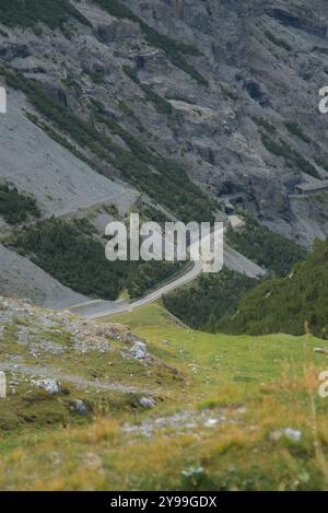 Scenic mountain road winding through the rugged terrain of Stelvio Pass in Italy, featuring sharp turns and tunnels carved into the mountainside. Stock Photo